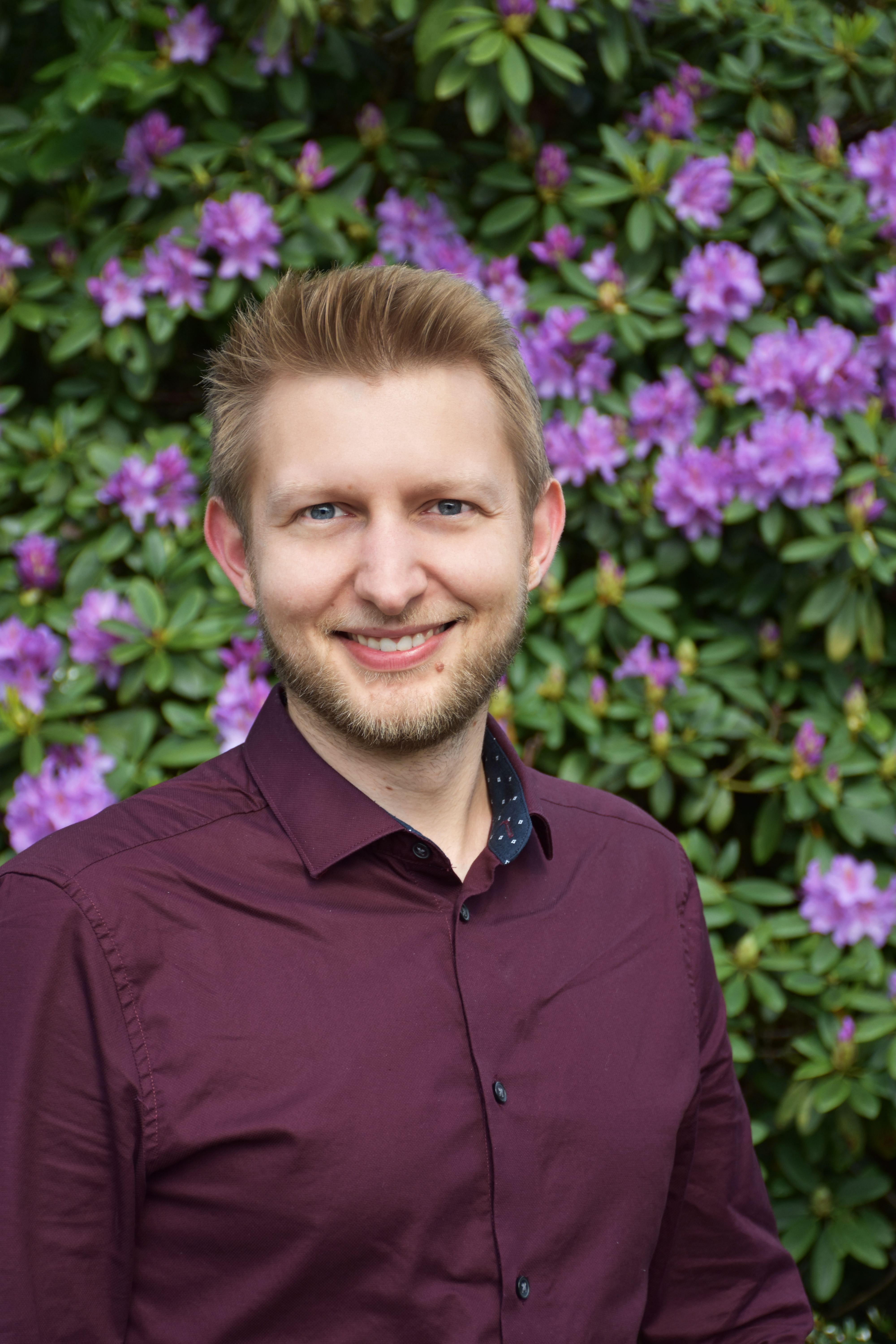 Mitarbeiter der Tourist-Information Wiefelstede vor einem lila blühenden Rhododendron
