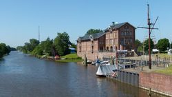 Blick über das Norder Tief am Hafen in Norden auf ein großes Backsteingebäude, das Alte Zollhaus.