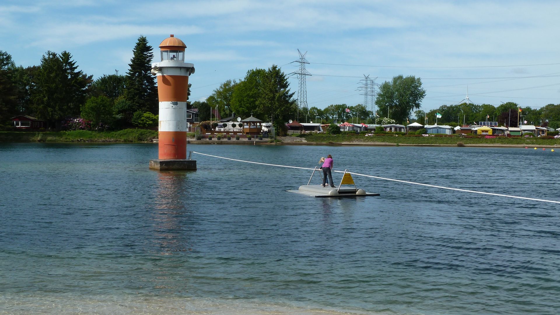 Ein Kind setzt vom Ufer mit dem Funfloß zum Leuchtturm im Bernsteinsee über