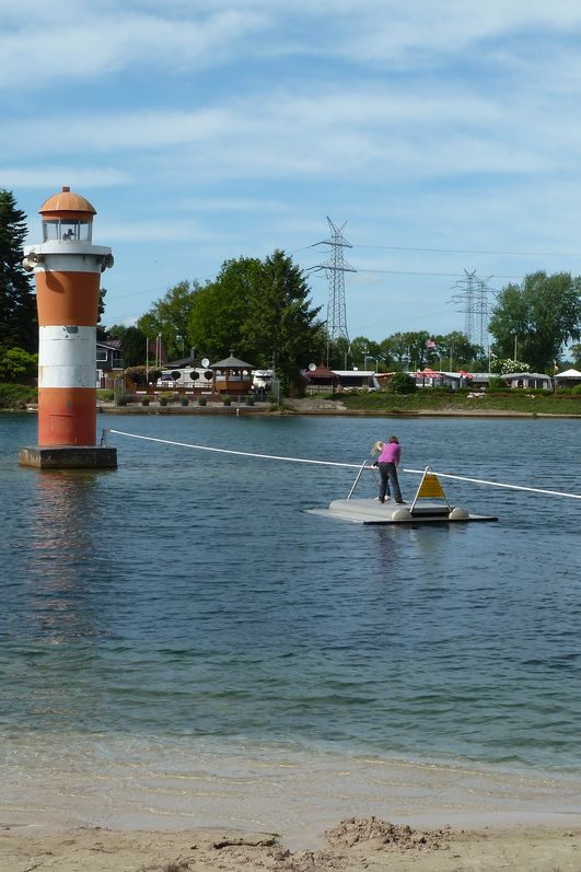 Ein Kind setzt vom Ufer mit dem Funfloß zum Leuchtturm im Bernsteinsee über