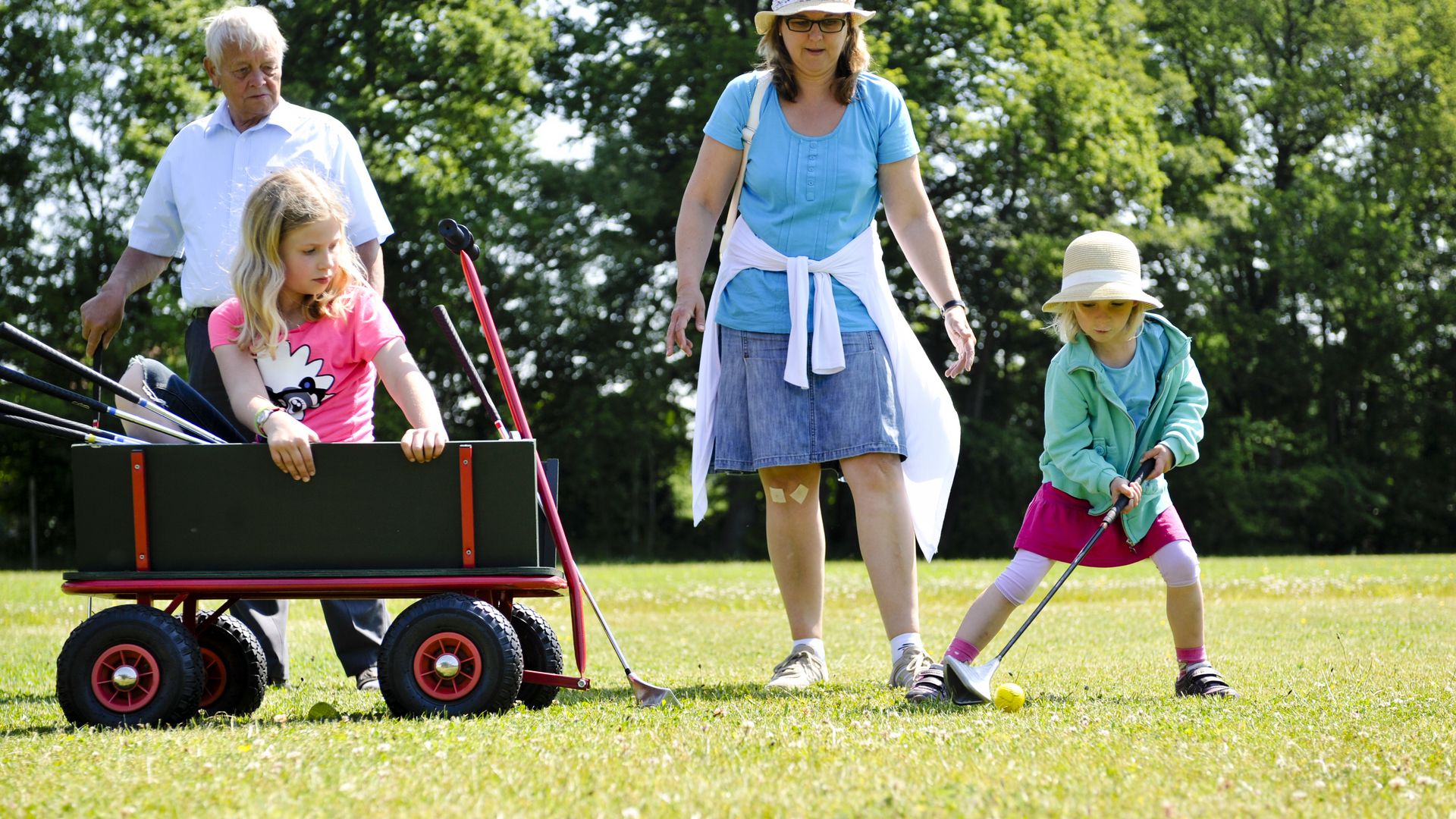 Familie bestehend aus Mutter, Opa und zwei Mädchen spielen Swingolf